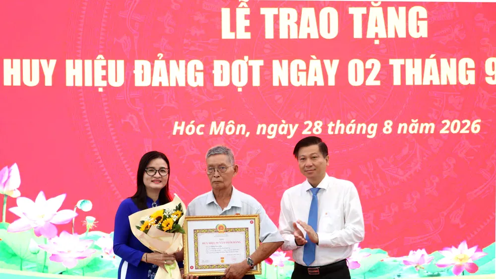 Đồng chí Trần Văn Tuấn - Ủy viên Ban Thường vụ Thành ủy, Trưởng Ban Nội chính Thành ủy TPHCM và Bí thư Đảng ủy xã Hóc Môn Lê Thị Ngọc Thanh trao Huy hiệu 55 năm tuổi Đảng đến đảng viên lão thành. Ảnh: NGÔ BÌNH