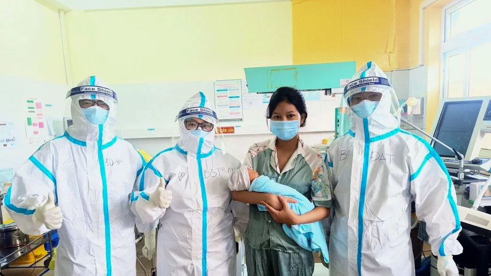 Chị M. lưu giữ tấm hình kỷ niệm với đội ngũ bác sĩ cứu sống chị cùng con trai. Ảnh: Bệnh viện dã chiến Hòa Vang