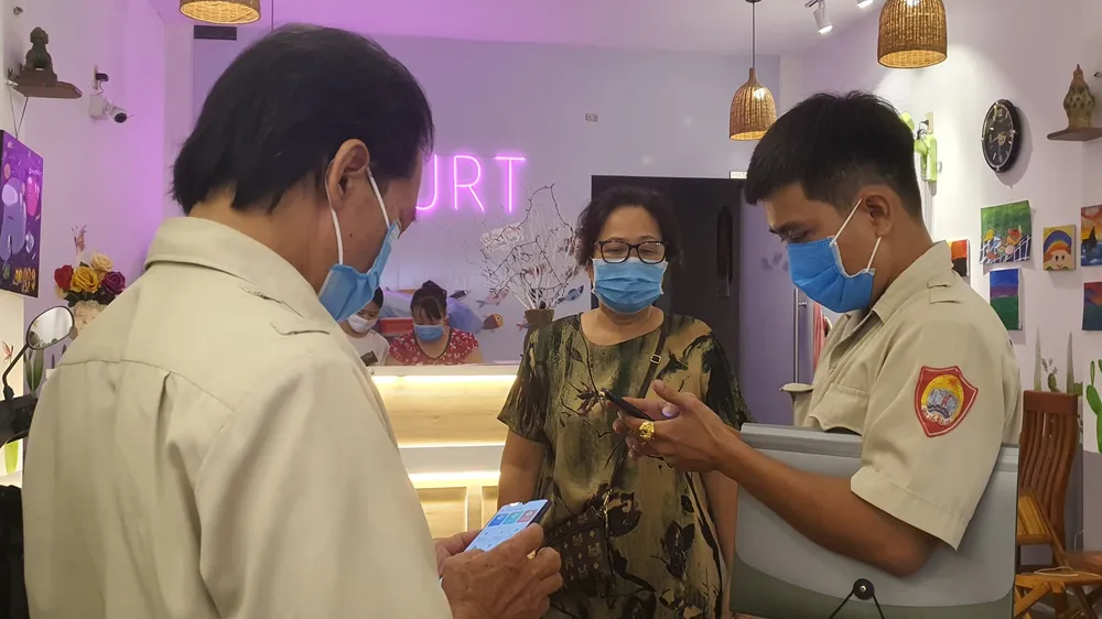 Lực lượng chức năng kiểm tra thực hiện quét mã QR tại 1 cơ sở kinh doanh dịch vụ ăn uống