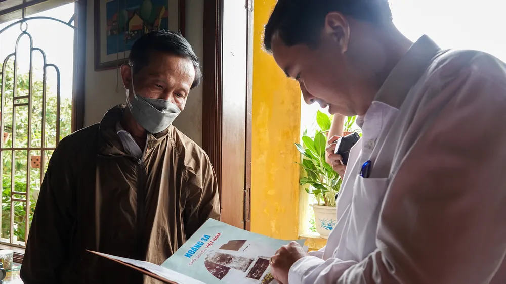 Ông Lê Phú Nguyện, Phó Chủ tịch UBND Hoàng Sa cùng gia đình nhân chứng Lê Châu (TP Hội An, tỉnh Quảng Nam) xem lại những tư liệu 