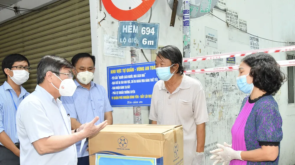Chủ tịch UBND TPHCM Nguyễn Thành Phong trao quà hỗ trợ người dân ở "vùng xanh" tại quận Phú Nhuận. Ảnh: VIỆT DŨNG