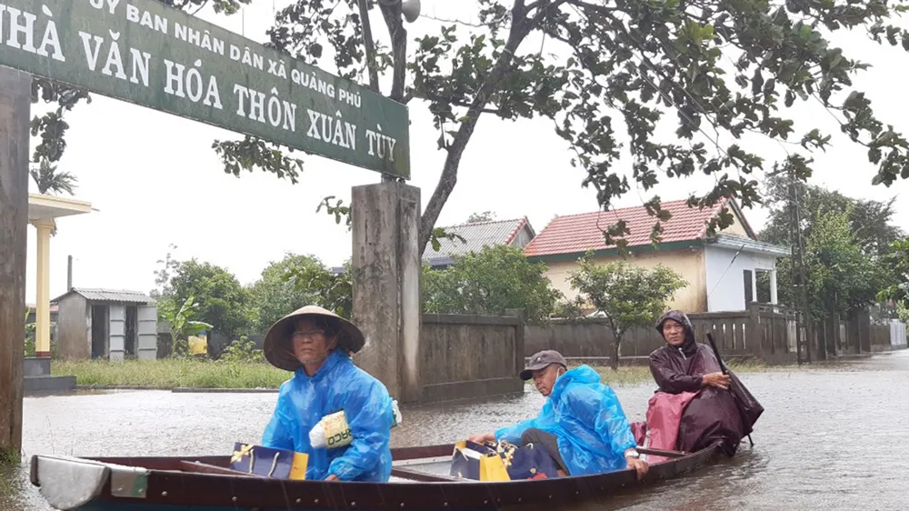 Người dân huyện Quảng Điền, tỉnh Thừa Thiên - Huế di chuyển trên đường ngập lụt, chiều 17-10. Ảnh: VĂN THẮNG