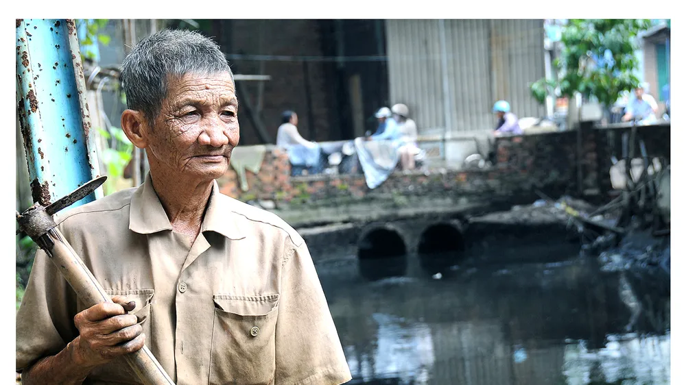 Bác Bảy Tân - nhân vật trong bộ ảnh “Người thầm lặng 30 năm vớt rác trên dòng kênh đen”. Ảnh: NSNA AN DUNG