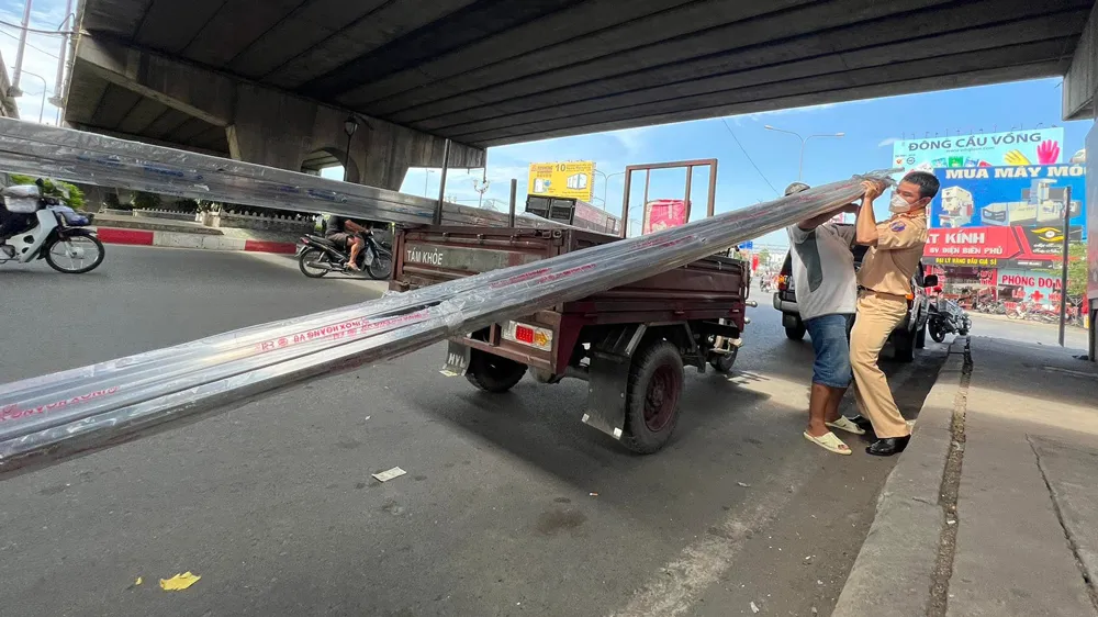 Lực lượng CSGT xử phạt một trường hợp chở vật liệu quá khổ trên quốc lộ 13, TP Thủ Đức, TPHCM. Ảnh: CHÍ THẠCH
