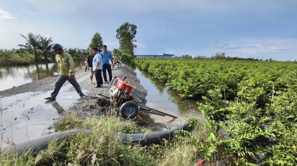 Người và phương tiện hút nước được điều động đến khu vực kênh Tràm Lầy 1, ấp 3, xã Bình Lợi để ứng phó ngập do triều cường và mưa lớn