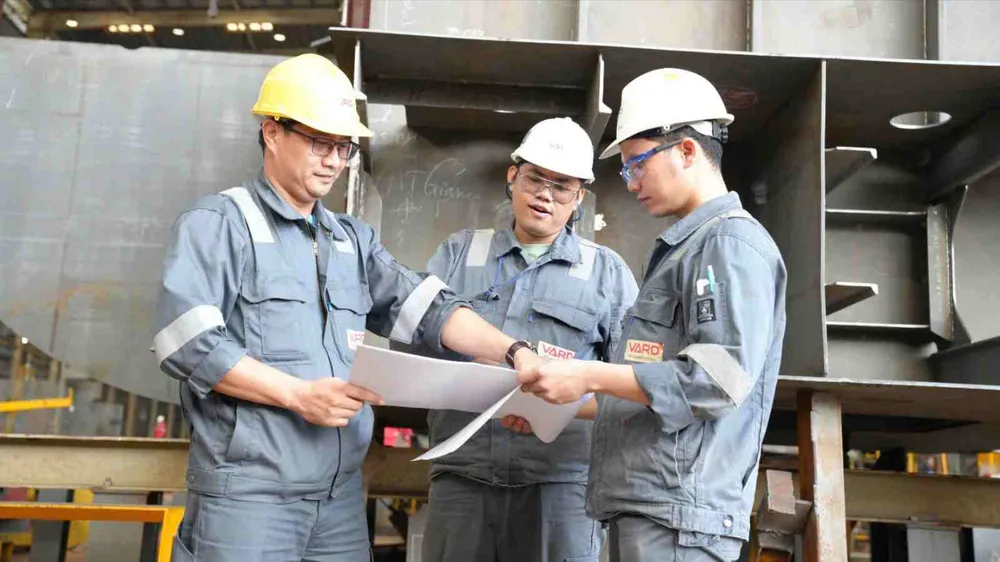 Kỹ sư Nguyễn Văn Lộc (bên trái) trao đổi kỹ thuật với đồng nghiệp trong giờ làm việc (ẢNH: TRÚC GIANG)