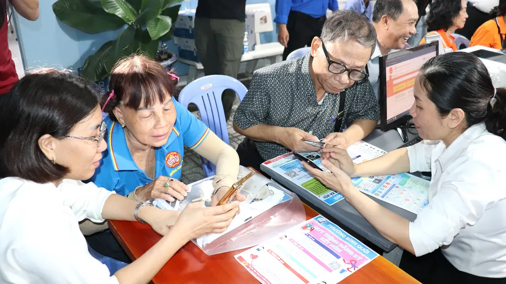 Cán bộ tổ địa bàn số phường Bình Quới hướng dẫn người cao tuổi sử dụng các ứng dụng trên điện thoại di động ngay tại khu dân cư (ẢNH: THÁI PHƯƠNG)