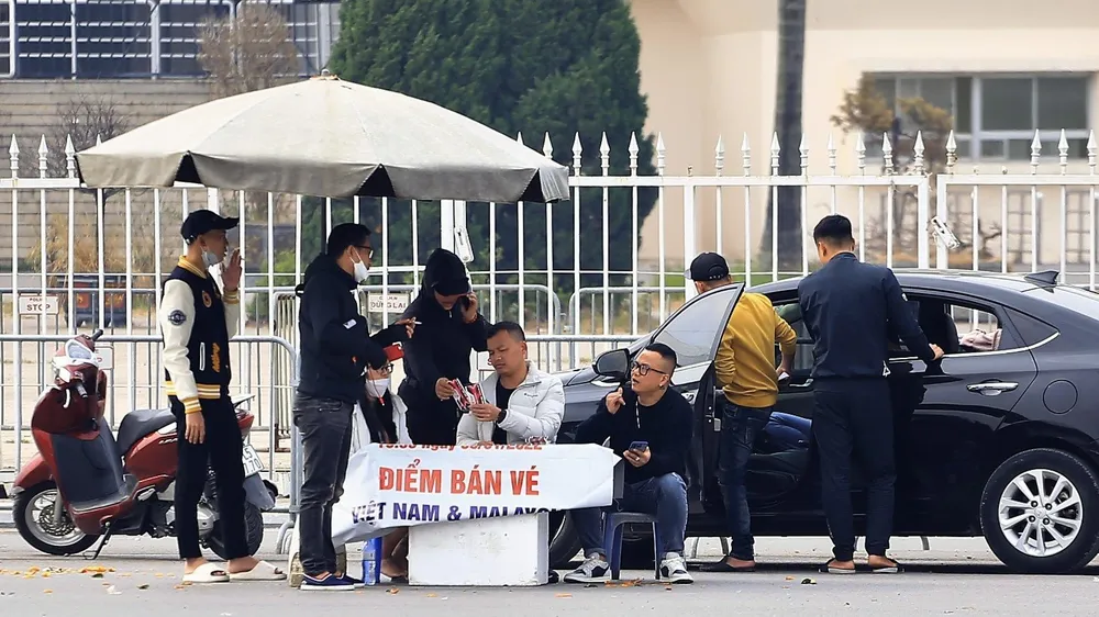 Một nhóm phe vé trước sân Mỹ Đình đã bán được vé "chợ đen" cho người đi ô tô. ẢNH: HỮU THÀNH