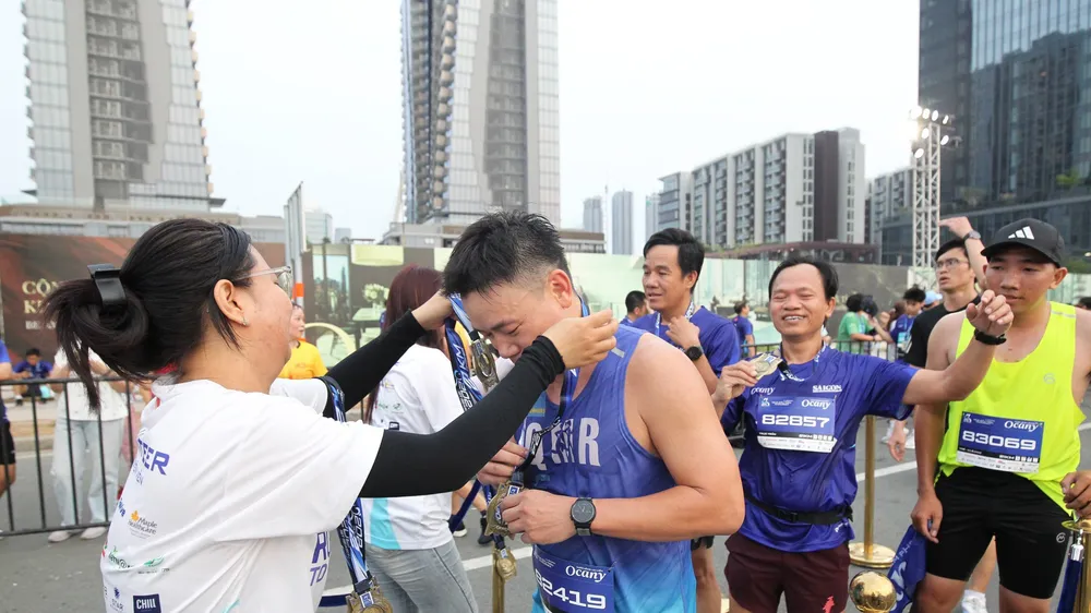Các tình nguyện viên trao huy chương cho các runner khi về đích. ẢNH: DŨNG PHƯƠNG 