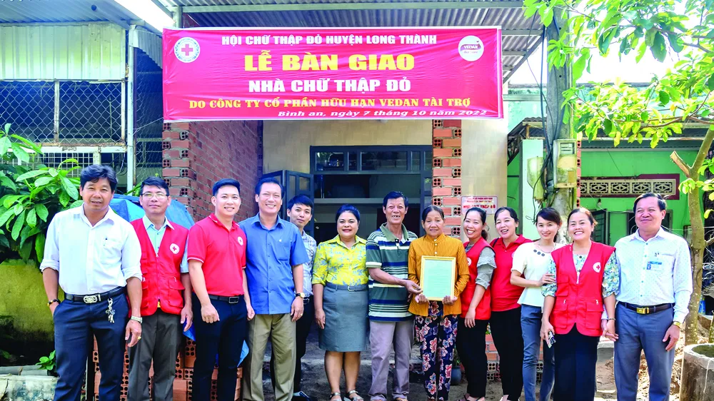 Bà Nguyễn Thu Thủy (thứ 6 từ trái sang) - đại diện Vedan trao nhà cho gia đình bà Huỳnh Thị Hồng tại xã Bình An