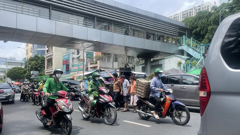 Ngay trước cổng Bệnh viện Bình Dân (quận 3, TPHCM) có cầu vượt bộ hành nhưng người dân vẫn băng qua đường Điện Biên Phủ mà không sử dụng cầu vượt