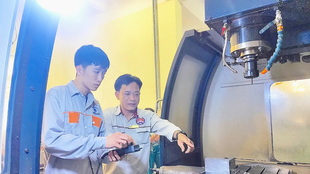 ThS Lê Thành Chung (phải), Trưởng khoa Cơ khí chế tạo, Trường Cao đẳng nghề Vĩnh Phúc, hướng dẫn sinh viên thực hành trên máy CNC 