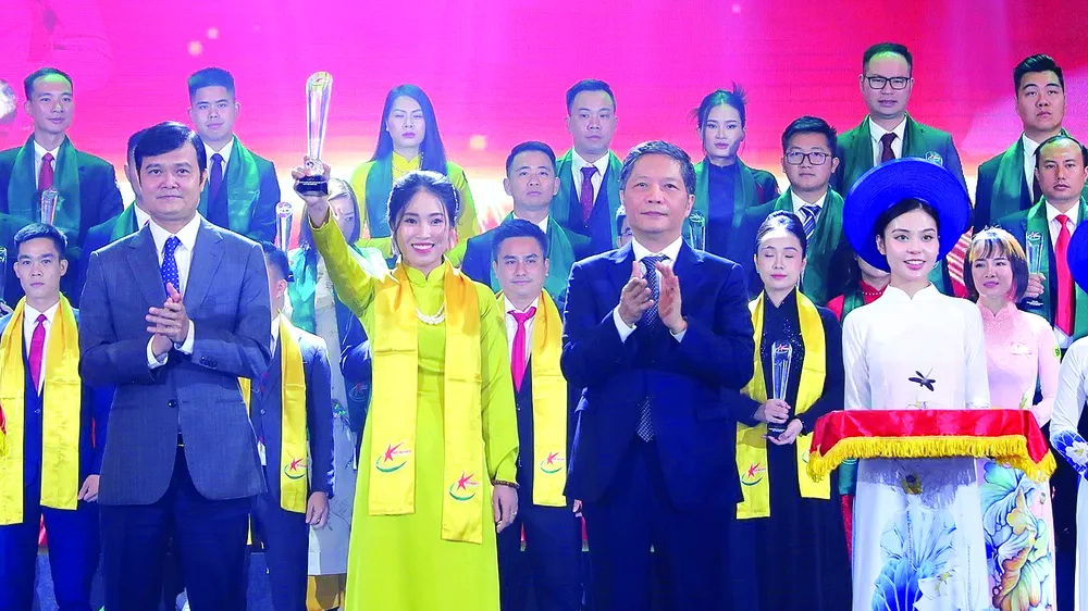 Trưởng Ban Kinh tế Trung ương Trần Tuấn Anh (phải) cùng Bí thư thứ nhất Trung ương Đoàn Bùi Quang Huy trao khăn và biểu trưng cho Chủ tịch kiêm Tổng Giám đốc Công ty Cổ phần Zoro Aya Nguyễn Thị Hạnh được vinh danh tốp 10 doanh nhân trẻ khởi nghiệp xuất sắc Ảnh: TTXVN