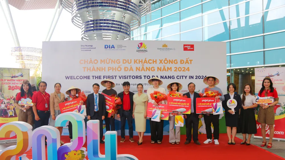 Những du khách quốc tế trên chuyến bay đầu tiên đến Đà Nẵng được nhận hoa và quà tặng. Ảnh: XUÂN QUỲNH