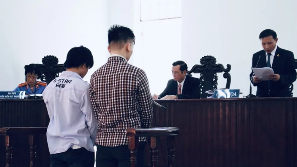 Hai bị cáo Nguyễn Hoàng Tuấn (áo kẻ) và Ôn Thành Tân tại phiên tòa sơ thẩm. Ảnh: THÀNH CHUNG