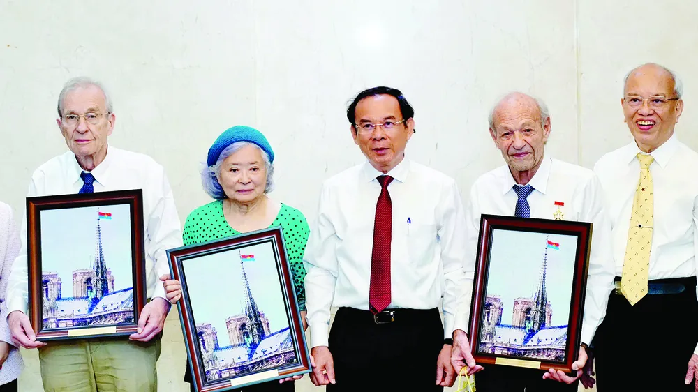 Bí thư Thành ủy TPHCM Nguyễn Văn Nên tặng ông Olivier Parriaux (bìa trái), ông Bernard Bachelard và bà Trần Tố Nga tranh gạo. Ảnh: HOÀNG HÙNG