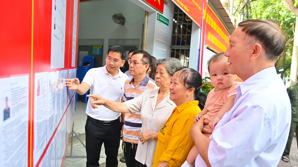 Lãnh đạo địa phương cùng các thành viên Tổ bầu cử Khu vực bầu cử số 30 phường Tam Thắng, cùng cử tri địa phương theo dõi thông tin tiểu sử các ứng cử viên