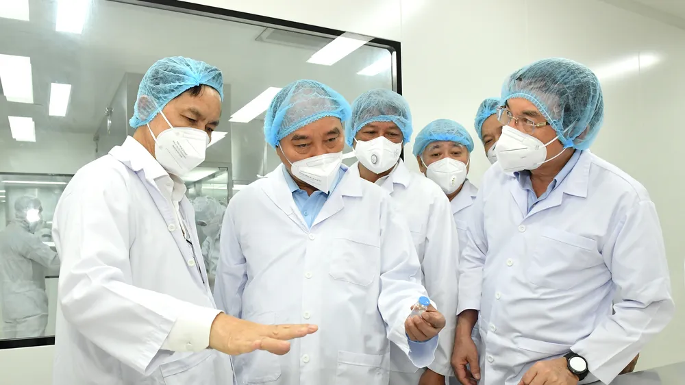 Chủ tịch nước Nguyễn Xuân Phúc và Bí thư Thành ủy TPHCM Nguyễn Văn Nên nghe giới thiệu về vaccine Nano Covax. Ảnh: VIỆT DŨNG