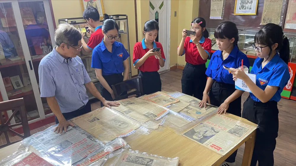 Cựu chiến binh Nguyễn Tiến Bình giới thiệu với các bạn trẻ về tư liệu, sách, báo được lưu giữ tại Không gian văn hóa Hồ Chí Minh. ẢNH: THẢO NGUYỄN