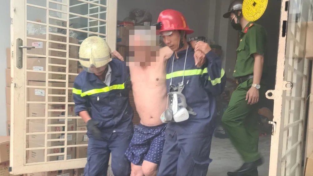 Lực lượng chức năng đưa người đàn ông lớn tuổi trong căn nhà cháy ra ngoài 