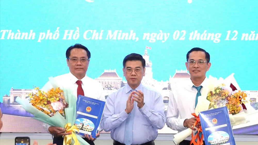 Phó Chủ tịch UBND TPHCM Nguyễn Văn Dũng trao quyết định và hoa chúc mừng ông Trương Công Huy và ông Phan Tấn Thảo