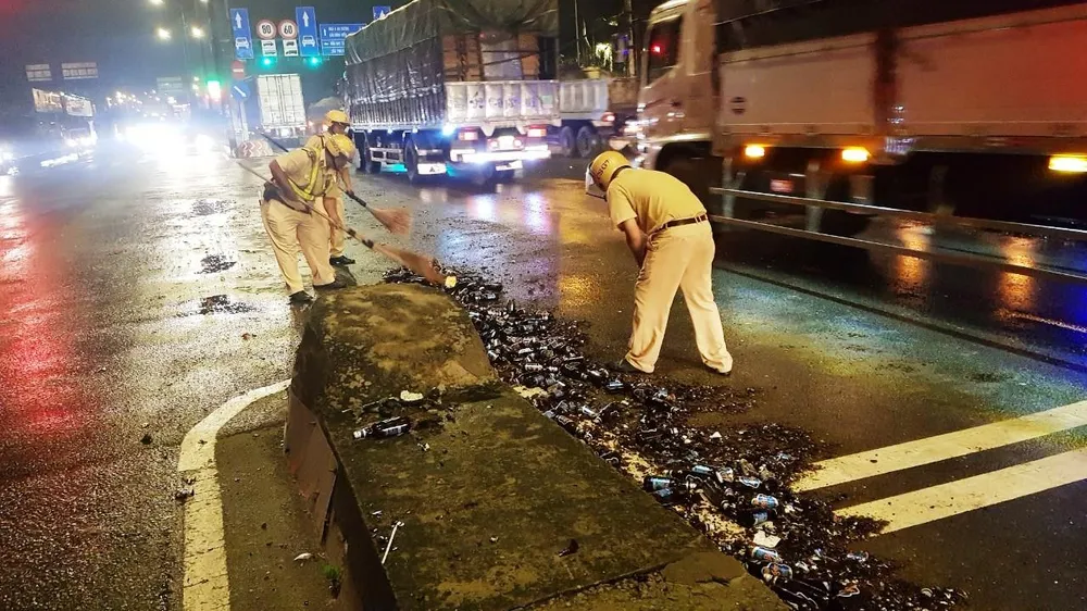 Cảnh sát giao thông hỗ trợ công nhân vệ sinh thu dọn vỏ chai đổ trên đường