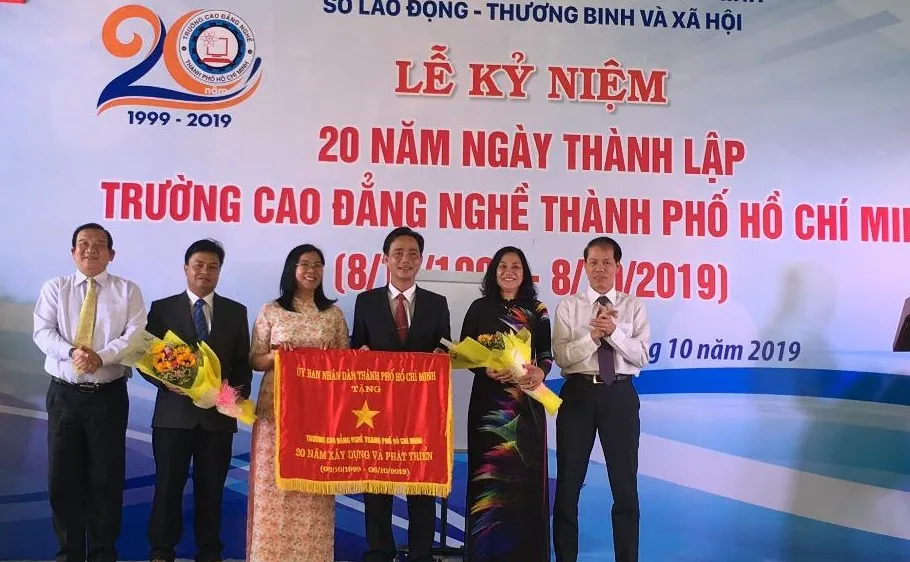 Ông Lê Minh Tấn, Giám đốc Sở LĐTB-XH TPHCM ( ngoài cùng bên trái) đại diện UBND TPHCM trao bức trướng của UBND TPHCM cho Ban Giám hiệu nhà trường