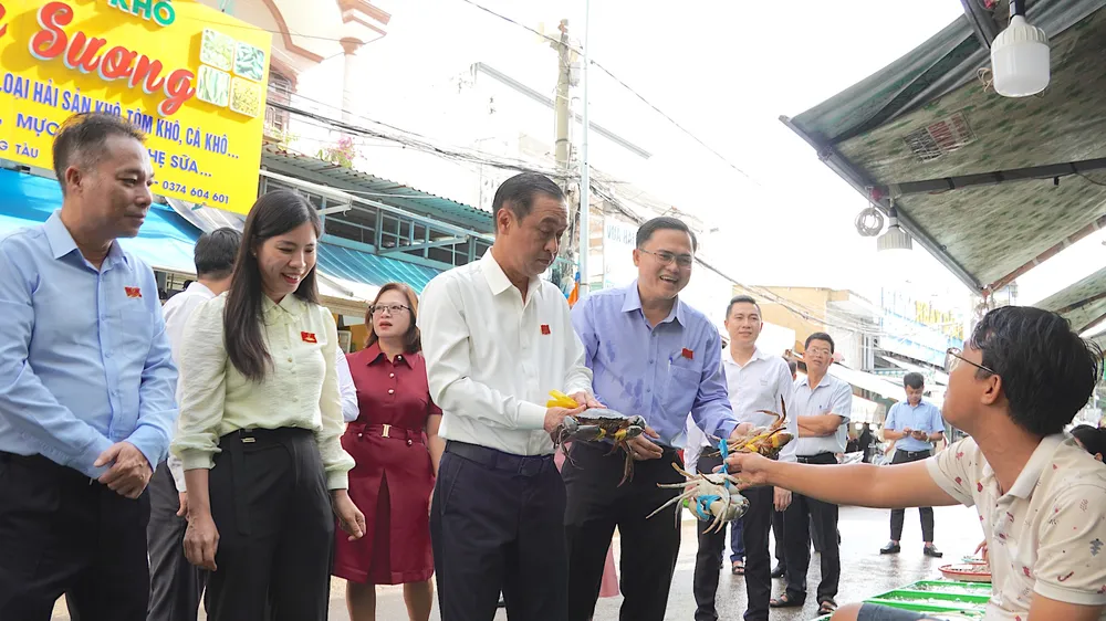 Đồng chí Huỳnh Thanh Nhân (thứ 3 từ trái vào) thăm hỏi hộ kinh doanh tại chợ hải sản Xóm Lưới. QUANG HUY