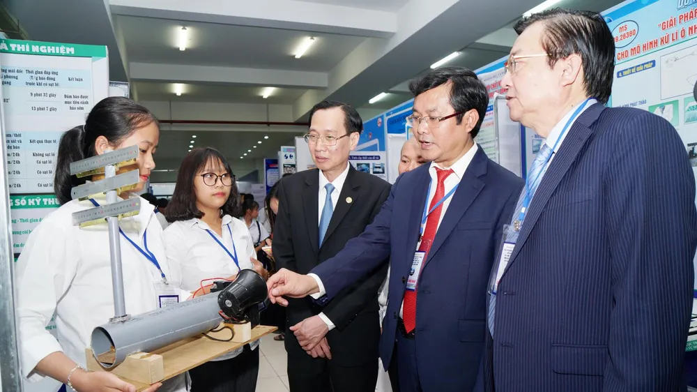 Từ phải qua: Các ông Hồng Sơn, Nguyễn Văn Phúc và ông Lê Thanh Liêm đang xem sản phẩm dự thi đề tài "Máy báo động sạc lỡ đất" của hai em học sinh trường THPT Trà My, tỉnh Quảng Nam. Ảnh: HOÀNG HÙNG