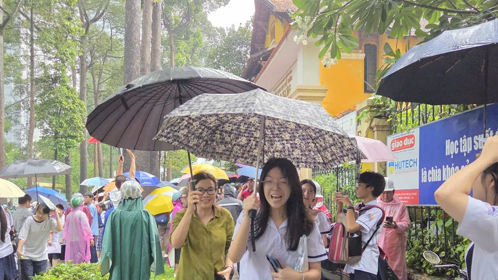 Thí sinh điểm thi THPT Trưng Vương ra về trong cơn mưa tầm tã. Ảnh: THU TÂM