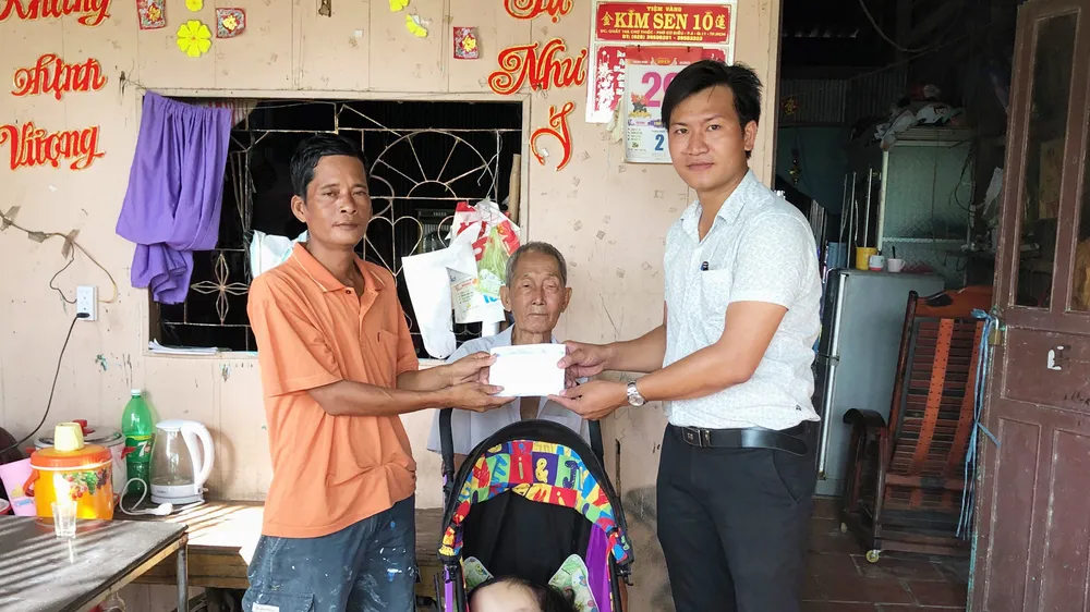 Đại diện Báo SGGP (bìa phải) trao tiền cho anh Lộc từ sự hỗ trợ của mạnh thường quân