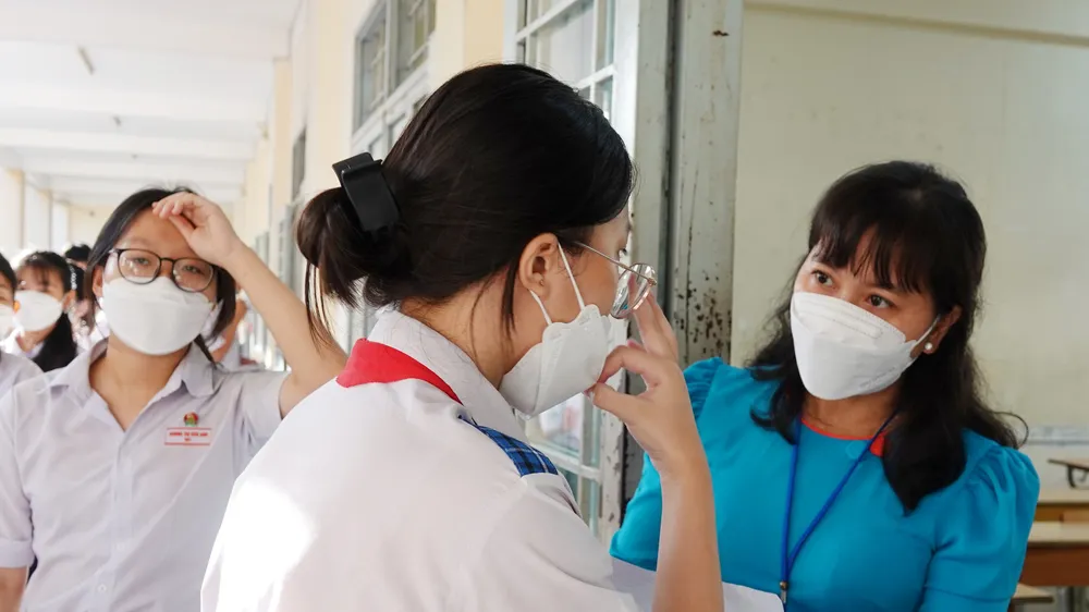 Giám thị kiểm tra giấy báo dự thi trước khi vào phòng thi. Ảnh: PHAN HUY