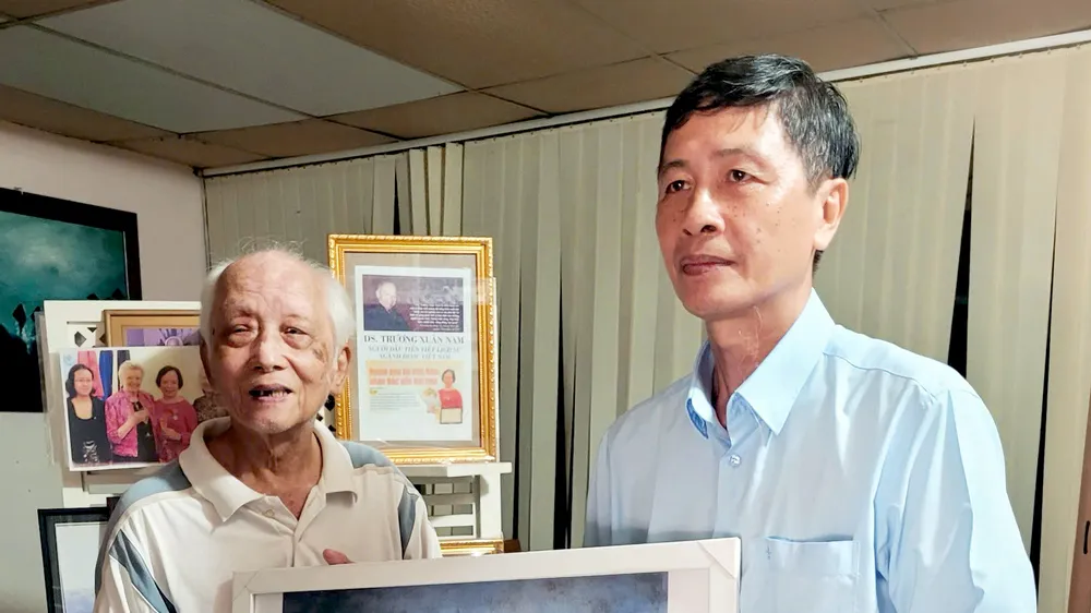 Ông Trần Tử Trung (bìa trái) tặng tranh của cha mình cho ông Lê Đình Lang