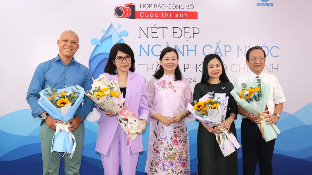 Tổng Biên tập Báo Phụ nữ TPHCM Lý Việt Trung (giữa) tặng hoa đến các thành viên Ban giám khảo cuộc thi 
