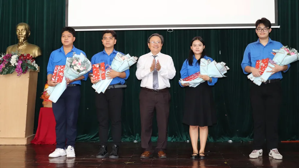 Thầy Phan Hường, Bí thư Đảng ủy, Hiệu trưởng Trường THPT Lê Thánh Tôn trao hoa và quà chúc mừng 4 đảng viên là học sinh