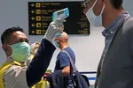 A health officer checks the temperature of an arriving passenger at Jakarta's Soekarno-Hatta International Airport. (Photo by Ken Kobayashi)
