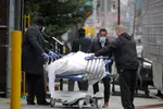 Các nhân viên vận chuyển một thi thể bên ngoài bệnh viện ở Brooklyn. (Ảnh: Reuters)