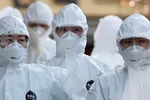 Medical workers in protective gear walk into a hospital facility to treat coronavirus patients in Daegu, South Korea, last month. © Reuters