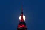 A supermoon rises behind the Empire State Building, glowing red in solidarity with coronavirus victims. © Reuters