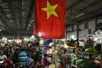 The Vietnamese flag is seen as vegetable vendors wait for customers at a wholesale market in Hanoi, Vietnam. — AFP 