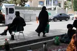 Một phụ nữ Afghanistan đi giữa những người lính Taliban tại một trạm kiểm soát ở Kabul, Afghanistan, ngày 6-7-2023.