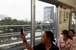 Người dân lưu lại hình ảnh đô thị bên ngoài khi trải nghiệm tuyến metro số 1. (Ảnh: Huyền Trinh/TTXVN)