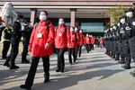 Policemen salute medical workers from Mongolia in Wuhan, Hubei Province on March 18. The workers had been brought to the province to help contain the coronavirus outbreak. © AP