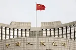 A Chinese flag flies in front of the People's Bank of China headquarters in Beijing, China, on Monday, Jan. 7, 2019. The central bank on Friday announced another cut to the amount of cash lenders must hold as reserves in a move to release a net 800 billio