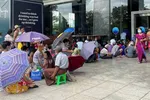 Người dân Yangon mang theo ghế đẩu và ô để khiến việc chờ đợi lâu bên ngoài các ngân hàng dễ chịu hơn. © Reuters