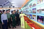 Visitors take a look at photos displayed at the exhibition on cooperation milestones among public security forces of Vietnam, Cambodia and Laos. (Photo: VNA)