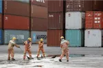 Workers clean the ground in front of containers at Tien Sa port in Da Nang city, Vietnam, March 6, 2020. REUTERS/Kham/File Photo