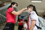 Học sinh trường Tiểu học Nghĩa Tân, quận Cầu Giấy được đo thân nhiệt và sát khuẩn tay trước khi vào lớp. (Ảnh: Thanh Tùng/TTXVN)