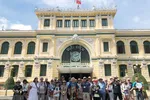 Đoàn khách quốc tế chụp ảnh lưu niệm trước Bưu điện Thành phố Hồ Chí Minh. (Ảnh: Mỹ Phương/TTXVN)