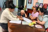 Công chức Trung tâm Phục vụ hành chính công xã Hóc Môn hỗ trợ cụ Lê Thị Tỷ thực hiện thủ tục hành chính tại nhà. Ảnh: HỮU TÂM